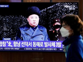 A woman walks past a TV broadcasting file footage for a news report on North Korea firing an unidentified projectile, in Seoul, South Korea, March 9, 2020.