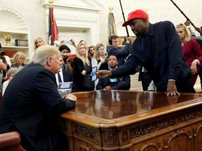 Rapper Kanye West shows President Donald Trump his mobile phone during a meeting in the Oval Office at the White House in Washington, U.S., October 11, 2018.