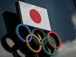 This file photo taken on August 24, 2020 shows the Olympic rings and the Japanese flag outside the Olympic Museum in Tokyo.