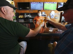 David Reay (L) and Casey Kemp enjoy some beers with bartender Tonya MacWilliams (middle) at the Fill Station Sports Bar in the Beach on Queen St. East. Bars and restaurants opened in Toronto as part of Phase 3 of COVID rules. People were enjoying socializing, social distancing watching sports at the on Saturday August 1, 2020.