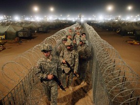 In this file photo, U.S. Army soldiers carry shotguns as they walk along a corridor separating what they deem to be the most extreme and dangerous detainees held inside the Camp Bucca detention centre located near the Kuwait-Iraq border, on May 19, 2008.