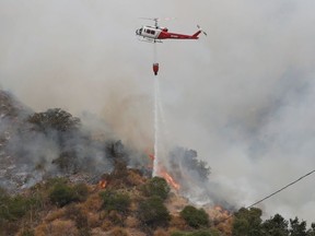 A helicopter drops water to help extinguish the Bobcat Fire, in Arcadia, California, U.S., September 13, 2020.