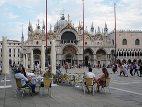 People sit at a cafe in St. Mark's Square as Venice gets ready to host the world's first film festival since the coronavirus outbreak August 29, 2020.