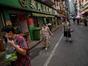 People walk along a street by a market in Wuhan, Hubei province, China. Friday, Sept. 4, 2020.