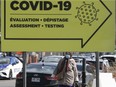 Making her way down Cote-des-Neiges a woman walks past sign for COVID testing at the Jewish General hospital in Montreal, Oct. 8, 2020.