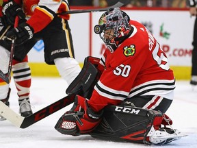 Corey Crawford of the Chicago Blackhawks makes a save off of his mask against the Calgary Flames at the United Center on December 02, 2018 in Chicago, Illinois.