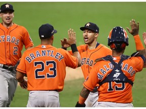 Carlos Correa, second from right, of the Houston Astros celebrates a 7-4 win against the Tampa Bay Rays with teammates Michael Brantley and Martin Maldonado in Game 6 of the American League Championship Series at PETCO Park on Oct. 16, 2020 in San Diego, Calif.