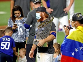 Justin Turner (centre) celebrates with the trophy after the L.A. Dodgers beat the Tampa Bay Rays to win the World Series on Tuesday night. Turner had received a positive COVID test earlier in the game and had been ordered off the field.
