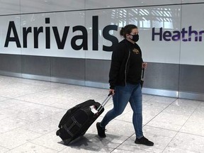 In this file photo taken on July 10, 2020, a passenger wearing a face mask or covering due to the COVID-19 pandemic, arrive at Heathrow airport, west London.