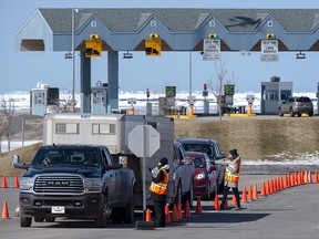 Provincial health department workers stop traffic that has crossed the Confederation Bridge in Borden-Carleton, P.E.I. on Sunday, March 22, 2020.