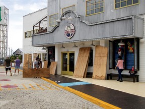 People stand next to plywood to board up a restaurant in preparation for the arrival of Hurricane Delta, in Cancun, Mexico October 6, 2020.