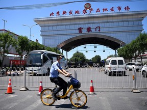 A member of security wearing a face mask cycles past the closed Xinfadi Market in Beijing on June 14, 2020.