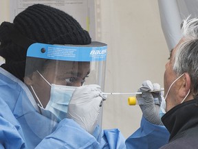 A health-care worker prepares to swab a man at a walk-in COVID-19 test clinic in Montreal North, Sunday, May 10, 2020.