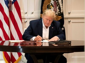 This White House handout photo released Saturday, Oct. 4, 2020 shows U.S. President Donald Trump working in the Presidential Suite at Walter Reed National Military Medical Center in Bethesda, Maryland on Oct. 3, after testing positive for COVID-19.
