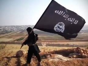 A file image grab taken from a video uploaded on YouTube on August 23, 2013 allegedly shows a member of Ussud Al-Anbar (Anbar Lions holding up the trademark black and white Islamist flag.