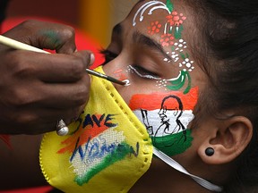 A student gets a her face painted to condemn the alleged gang-rape of a 19-year-old woman by four men in Bool Garhi village of Uttar Pradesh state, in Mumbai on October 2, 2020.