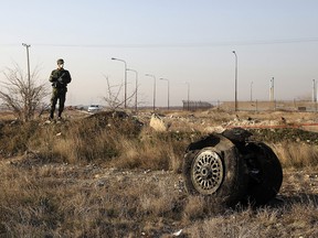 A police officer stands guard as debris is seen from an Ukrainian plane which crashed in Shahedshahr, Iran, January 8, 2020.