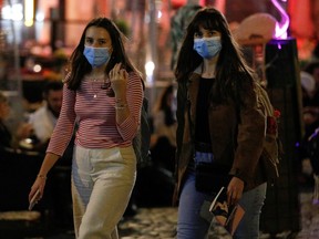 Women wearing face masks walk as local authorities in the Italian capital Rome order face coverings to be worn at all times outdoors in an effort to counter rising COVID-19 infections, in Rome, Italy, Tuesday, Oct. 6, 2020.