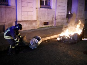 An Italian fire-fighter extinguishes a burning bin during a protest of far-right activists against the government restriction measures to curb the spread of COVID-19, in Turin, Monday, Oct. 26, 2020.