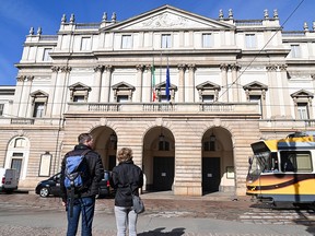 Two people look at the La Scala theatre, in central Milan, on February 24, 2020.