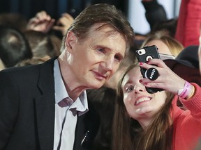 Liam Neeson poses for a selfie with a fan on the red carpet during the Toronto International Film Festival in Toronto on Saturday September 8, 2018.