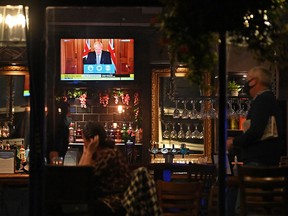 A television shows Britain's Prime Minister Boris Johnson speaking as customers sit at the bar inside the William Gladstone pub in Liverpool, north west England on October 12, 2020.