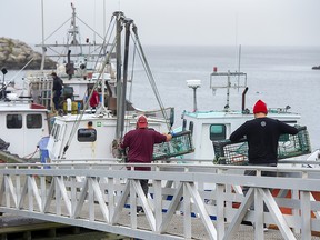 Indigenous fishermen carry lobster traps in Saulnierville, N.S. on Wednesday, Oct. 21, 2020.