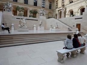 Visitors wearing protective face masks look at statues inside the deserted Louvre Museum as the novel coronavirus Covid-19 pandemic keeps the tourists away, in Paris on October 14, 2020.