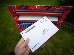 In this photo illustration, a provincial election mail-in ballot sealed in an Elections B.C. return envelope is seen before being deposited in a Canada Post mailbox, in Richmond, B.C., Saturday, Oct. 17, 2020.