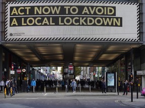 A pandemic lockdown warning sign is displayed to shoppers in Manchester, England, Wednesday, Oct. 7, 2020. Manchester now has the highest COVID-19 infection rate in the country, with nearly 600 cases per 100,000 people.
