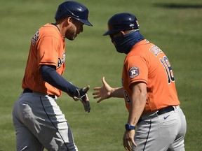 George Springer of the Houston Astros celebrates his home run against the Oakland Athletics with third base coach Omar Lopez during Game 2  of the American League Division Series at Dodger Stadium on October 6, 2020.