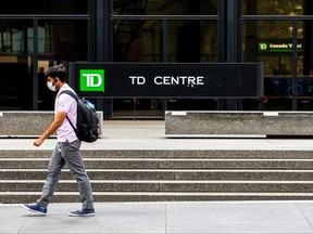 A man wearing a protective face mask walks by TD Bank in the financial district in Toronto, June 24, 2020.