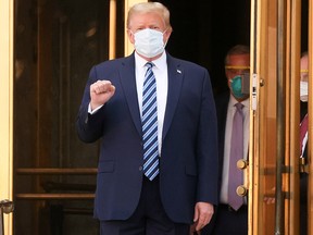 President Donald Trump makes a fist as he walks out the front doors of Walter Reed National Military Medical Center after a fourth day of treatment for the coronavirus disease while returning to the White House in October 5, 2020.