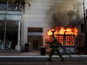 A firefighter prepares to extinguish a fire in a structure of The Grove shopping center during a protest against the death in Minneapolis police custody of George Floyd, in Los Angeles, California, U.S., May 30, 2020.
