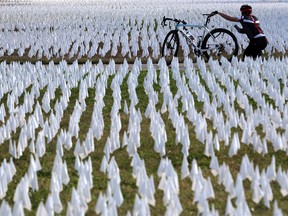 A cyclist takes pictures of the public art project “IN AMERICA How could this happen…” on the DC Armory Parade Ground October 23, 2020 in Washington.