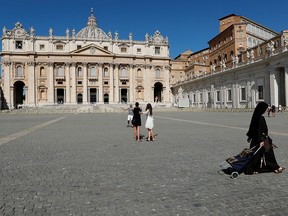 A nun passes by tourists taking pictures on St. Peter's Square as Pope Francis gives his weekly general audience virtually from a library inside the Vatican August 5, 2020.