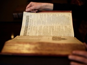 A worker poses with a first edition of the First Folio, the first collected edition of William Shakespeare's works, containing 36 plays, at Christie's auction house in London, Britain April 19, 2016.
