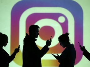 Silhouettes of mobile users are seen next to a screen projection of the Instagram logo in this picture illustration taken March 28, 2018.