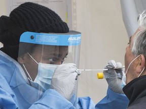 A health-care worker prepares to swab a man at a walk-in COVID-19 test clinic in Montreal North, Sunday, May 10, 2020, as the COVID-19 pandemic continues in Canada and around the world.