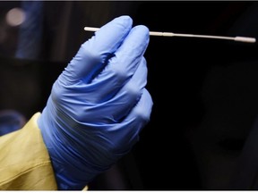 A nurse uses a swab to perform a test on a patient at a drive-in COVID-19 clinic in Montreal, on Wednesday, October 21, 2020.