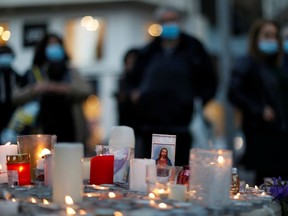 People gather near candles and flowers to pay tribute to the victims of a deadly knife attack in front of the Notre Dame church in Nice, France, October 30, 2020.