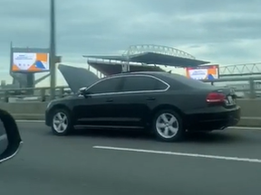 A car is seen driving with its hood up along the Gardiner Expressway. The video was uploaded to Reddit on Sunday by user @stretch2099.