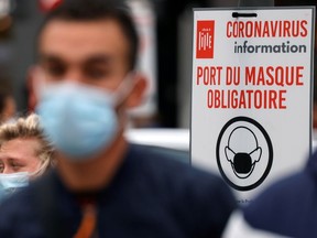 People walk past a placard that reads "Mandatory to wear a mask" in the streets of Lille as the coronavirus disease (COVID-19) outbreak continues in France, October 8, 2020.