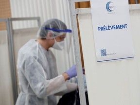 A healthcare worker takes a swab sample from a person at a coronavirus disease (COVID-19) testing centre in Paris, France, October 13, 2020.