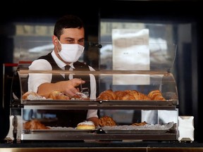 A waiter wearing a protective face mask works at a bar as the outbreak of the coronavirus disease (COVID-19) continues, in Rome, Italy, October 25, 2020.