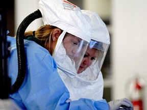 Healthcare workers wearing powered air purifying respirator (PAPR) hoods process COVID-19 test samples at a drive-thru testing site in Sioux Falls, South Dakota, Wednesday, Oct. 28, 2020.