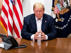 This handout photo released by the White House shows U.S. President Donald Trump and his Chief of Staff (not pictured) participating in a phone call with the U.S. Vice President, Secretary of State and Chairman of the Joint Chiefs of Staff on Oct. 4, 2020, in his conference room at Walter Reed National Military Medical Center in Bethesda, Md.