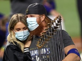 Justin Turner of the Los Angeles Dodgers and his wife Kourtney Pogue, hold the Commissioners Trophy after the teams 3-1 victory against the Tampa Bay Rays in Game Six to win the 2020 MLB World Series at Globe Life Field on October 27, 2020 in Arlington, Texas.