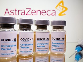 Vials with a sticker reading, "COVID-19 / Coronavirus vaccine / Injection only" and a medical syringe are seen in front of a displayed AstraZeneca logo in this illustration taken Oct. 31, 2020.