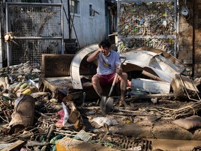 A man reacts as he takes a break from cleaning mud outside his house, which was submerged due to floods caused by Typhoon Vamco, in Marikina, Metro Manila, Philippines, Nov. 13, 2020.